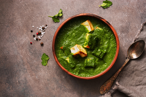 Palak paneer or Spinach and Cottage cheese curry on a dark background. Traditional Indian food. Top view, copy space