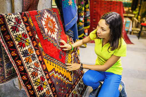 woman chooses oriental carpet at market in Turkey