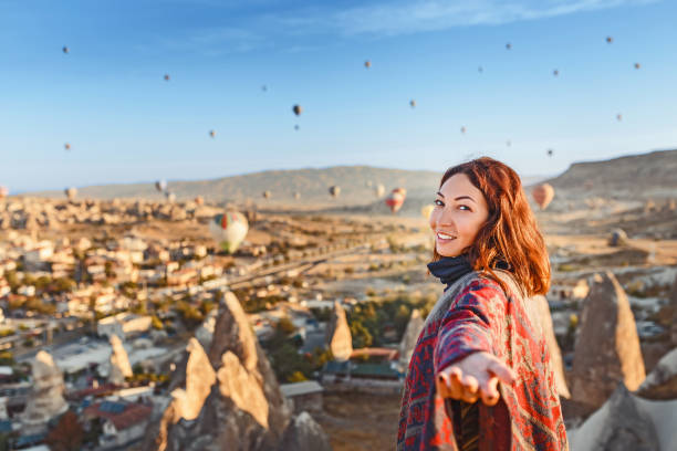 femme regardant à des ballons colorés d’air chaud survolant la vallée à la cappadoce. suivez-moi et voyage en turquie concept - hot air balloon flying heat people photos et images de collection