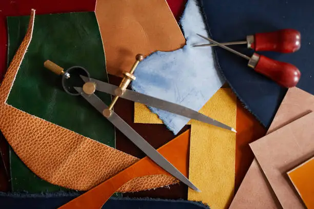 Background image of leather cuts and tools scattered on table in tanners workshop, copy space