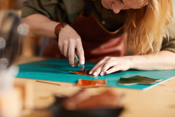 Leather Craftsman Closeup Warm toned close up of young female artisan making leather bag in workshop, copy space clothing design studio photos stock pictures, royalty-free photos & images