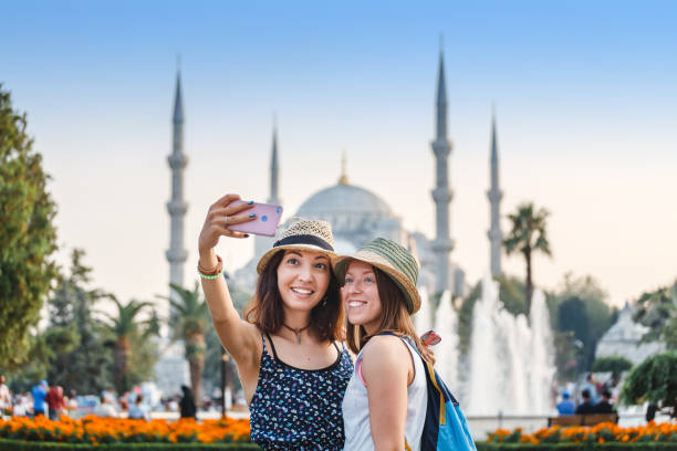 Two smiling girlfriends with smart phone doing selfie in front of the Blue Mosque in Istanbul. Travel and vacation in Turkey concept stock photo