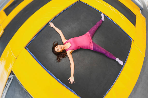 Young woman is resting and lying on a trampoline after doing some exercise session, concept of hard workout