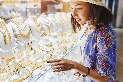 Woman in hat looking to showcase or shop window and chooses a golden luxury jewelry