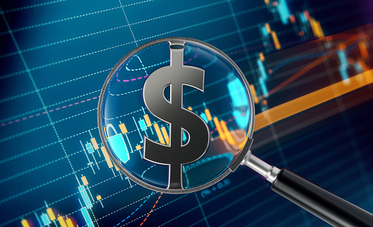 Magnifier focusing on American Dollar sign and financial analysis graph. Selective focus. Horizontal composition with copy space.