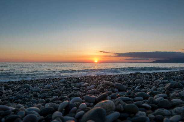 istock Pebble beach at beautiful sunset. Distant mountains in clouds. 1146301531