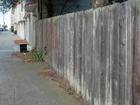 Unpainted wooden fence in a quiet neighborhood street in the daytime