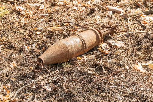 Old rusty unexploded ordnance of wartime times in the forest