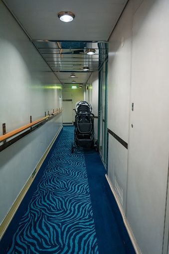 Empty cabin corridor of a ship with a stroller outside one of the cabins