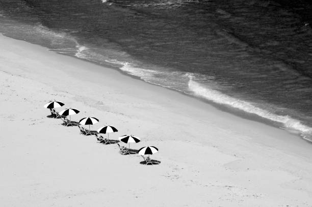 Overhead view of beach chairs and surf of the Atlantic Ocean in West Palm Beach, Florida captured in black and white Overhead view of beach chairs and surf of the Atlantic Ocean in West Palm Beach, Florida captured in black and white black and white beach stock pictures, royalty-free photos & images