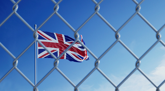 Fence in front of British flag. Illegal immigration concept. Horizontal composition with copy space.