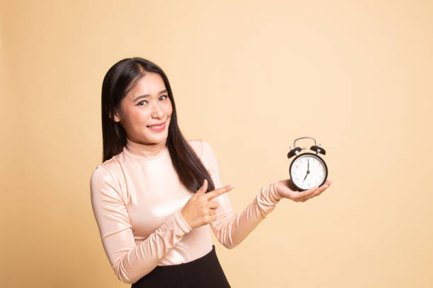 istock Young Asian woman point to a clock. 1146308586