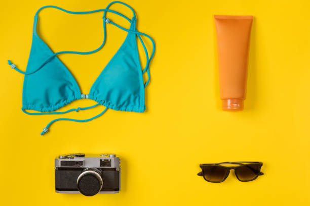 istock swimsuit, sunscreen, camera, sunglasses on a yellow background, top view 1146311084