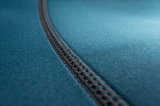 Close up of stitching along the seam of a blue neoprene diving wetsuit