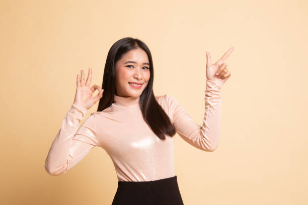 istock Young Asian woman point and show OK. 1146312500