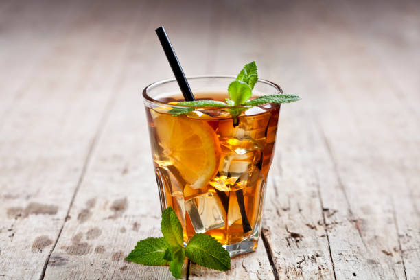 Traditional iced tea with lemon, mint leaves and ice cubes in glass on rustic wooden table stock photo