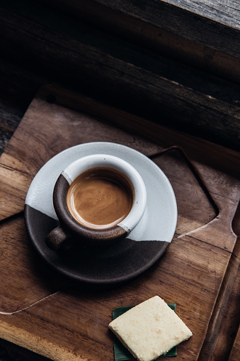Overhead espresso coffee in a black and white ceramic cup on wooden table at coffee shop. Drink photography concept, minimalism, close up