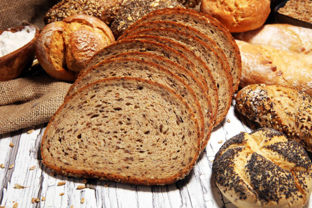 istock Assortment of baked bread and bread rolls on rustic white bakery table background 1146313134