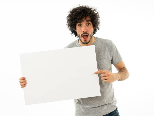 istock Funny and good looking millennial man showing and pointing at blank board with copy space for advertisement text. Looking happy surprised and shocked at great ad. In marketing concept. 1146318603