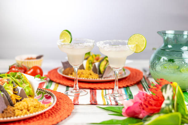 Margarita glasses with salted rim and lime and plates of tacos stock photo