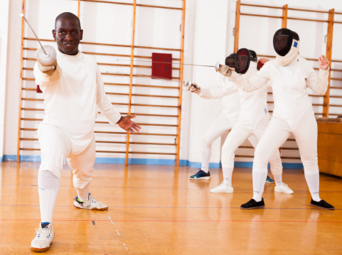 Sporty african american man fencer practicing effective fencing techniques in training room