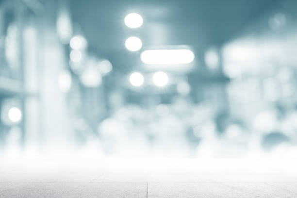 Perspective cement table top texture white blur modern interior retail shop business background. Abstract window light bokeh effect of coffeeshop counter concept for blurry office break dessert breakfast, defocus cafe restaurant mockup product montage