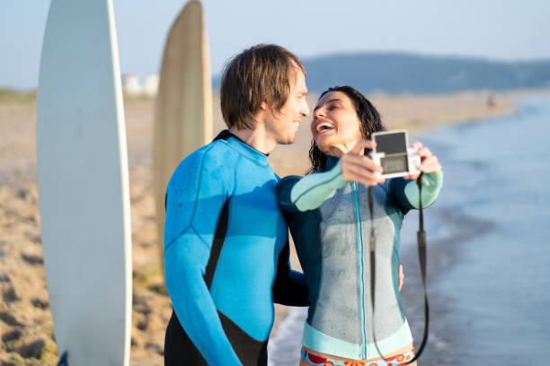 istock Couple surfers taking selfie with camera, on beach 1146354783