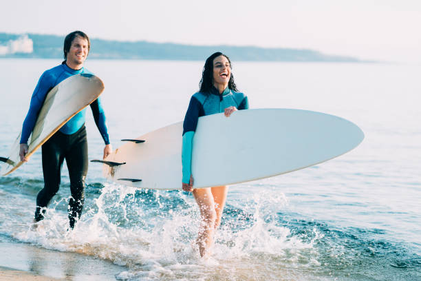 istock Couple surfers walking in water on beach 1146354787