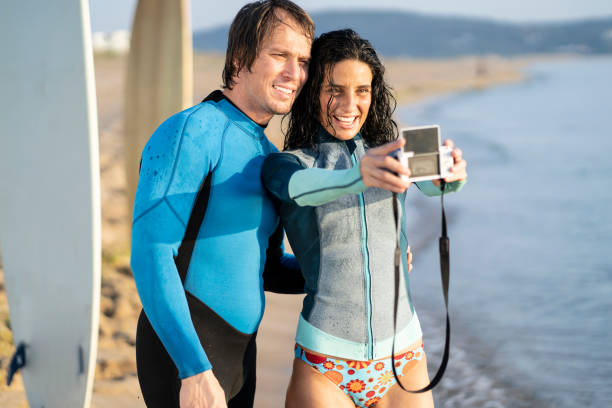 istock Couple surfers taking selfie with camera, on beach 1146354791