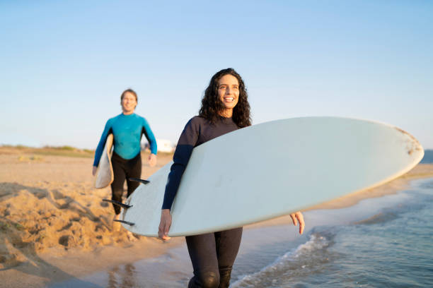 istock Couple surfers walking in water on beach 1146354804
