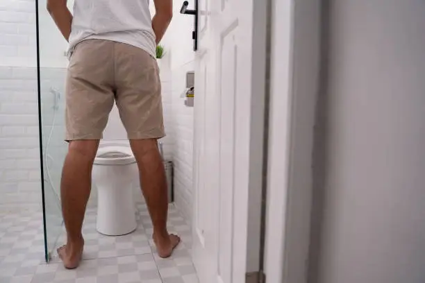 back portrait of man's gesture peeing in a toilet