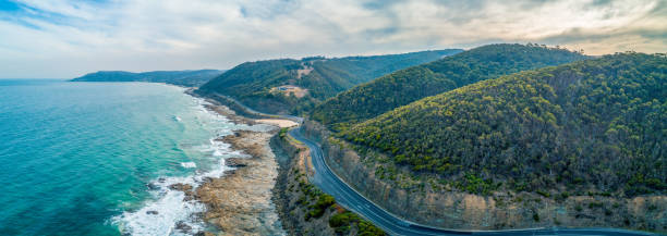 Great Ocean Road passing through scenic landscape in Victoria, Australia - aerial panoramic landscape stock photo