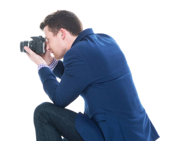 istock Side view of handsome man crouching while holding DSLR camera 1146365835