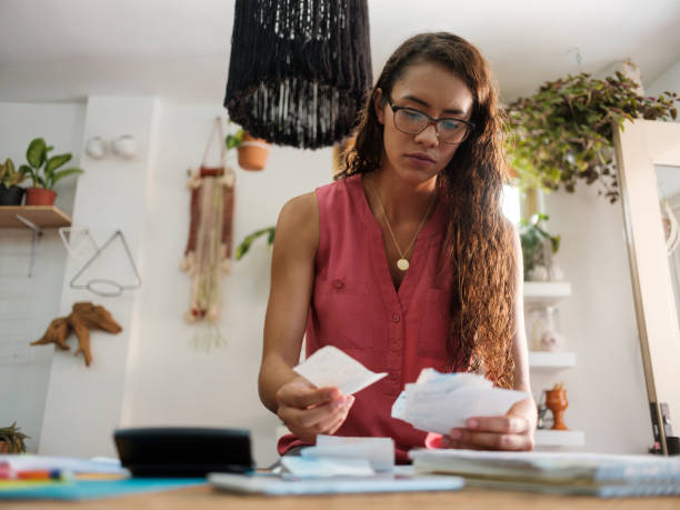 Young latin woman holding receipts and looking at them. - fotografia de stock