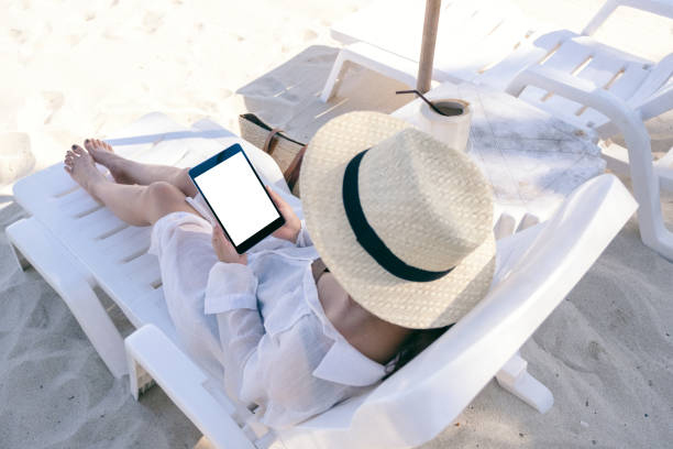 istock a woman holding a black tablet pc with blank desktop screen while laying down on beach chair 1146370587