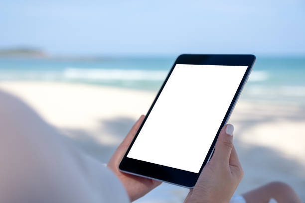 istock a woman holding a black tablet pc with blank desktop screen while laying down on beach chair 1146370591