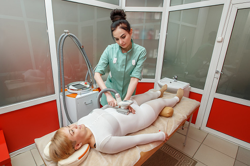 Woman having anti-cellulite lpg massage treatment with apparatus in beauty salon