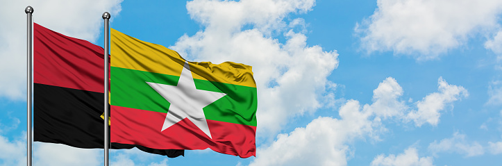 Angola and Myanmar flag waving in the wind against white cloudy blue sky together. Diplomacy concept, international relations.