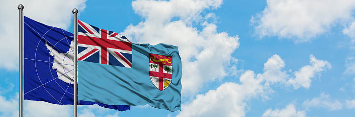 Antarctica and Fiji flag waving in the wind against white cloudy blue sky together. Diplomacy concept, international relations.