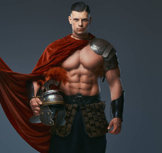 istock Brutal ancient Greece warrior with a muscular body in battle uniforms holds a helmet while standing in a studio. 1146414297