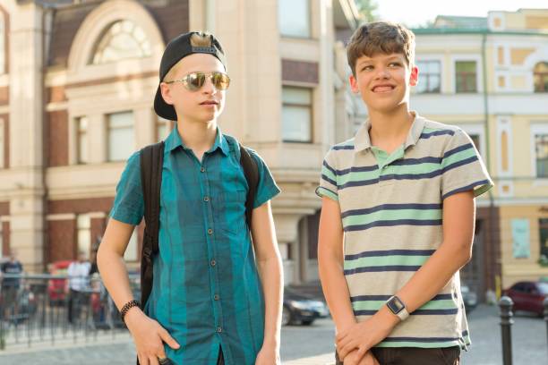 outdoor portrait of two friends boys teenagers 13, 14 years old talking and laughing on city street - 13 14 years teenager school education imagens e fotografias de stock