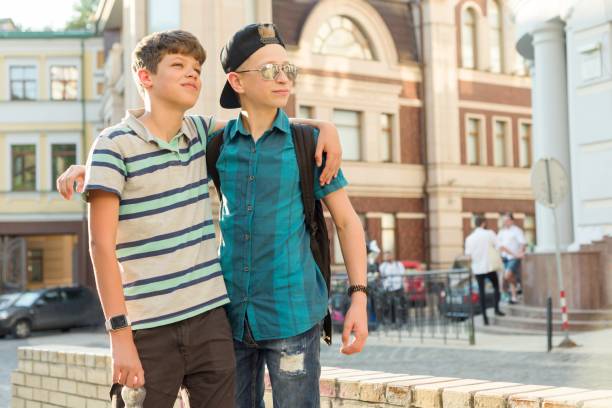 odkryty portret dwóch przyjaciół chłopców nastolatków 13, 14 lat mówi i śmieje się na ulicy miasta - friendship early teens 13 14 years city street zdjęcia i obrazy z banku zdjęć