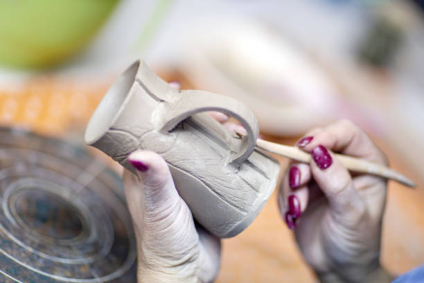 Hands of artist who make a mug from ceramic clay in studio