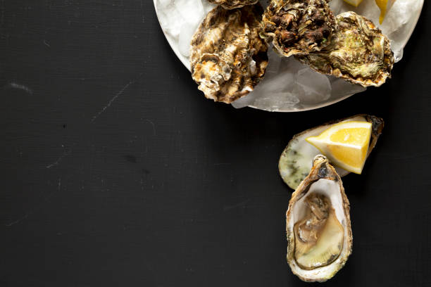 istock Fresh oysters on a black surface, top view. Overhead, from above, flat lay. Copy space. 1146416780