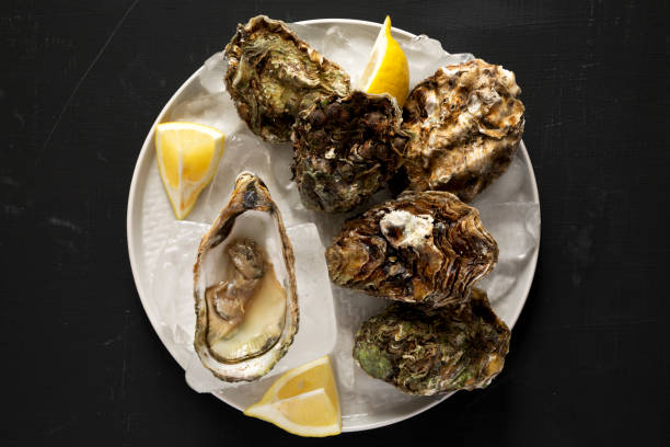 istock Fresh oysters on a plate over black surface, view from above. Overhead, flat lay, top view. Close-up. 1146416808