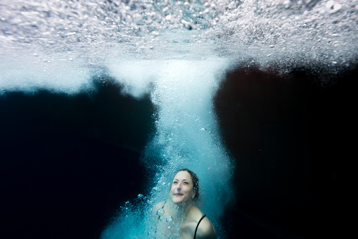 A woman has plunged into the freezing water of the Antarctic ocean and is rising back to the light at the surface with her eyes open, Antarctic Peninsula