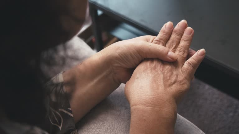 Asian senior woman sitting on a couch having a hand pain.massage on her hand