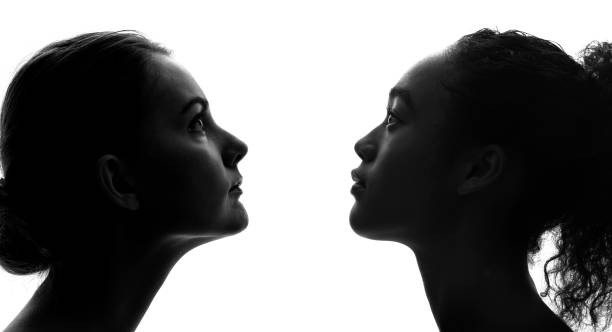 silhouettes d’une femme blanche et d’une femme noire. - horizontal black and white toned image two people photos et images de collection