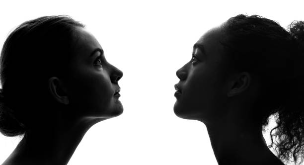 sylwetki białej kobiety i czarnej kobiety. - horizontal black and white toned image two people zdjęcia i obrazy z banku zdjęć
