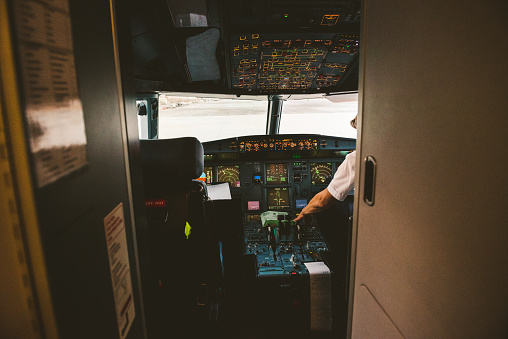 Santorini airport, Thera, Greece - October 13, 2018, Captain in cockpit preparing to take off from Santorini airport. View from the hall towards instruments.